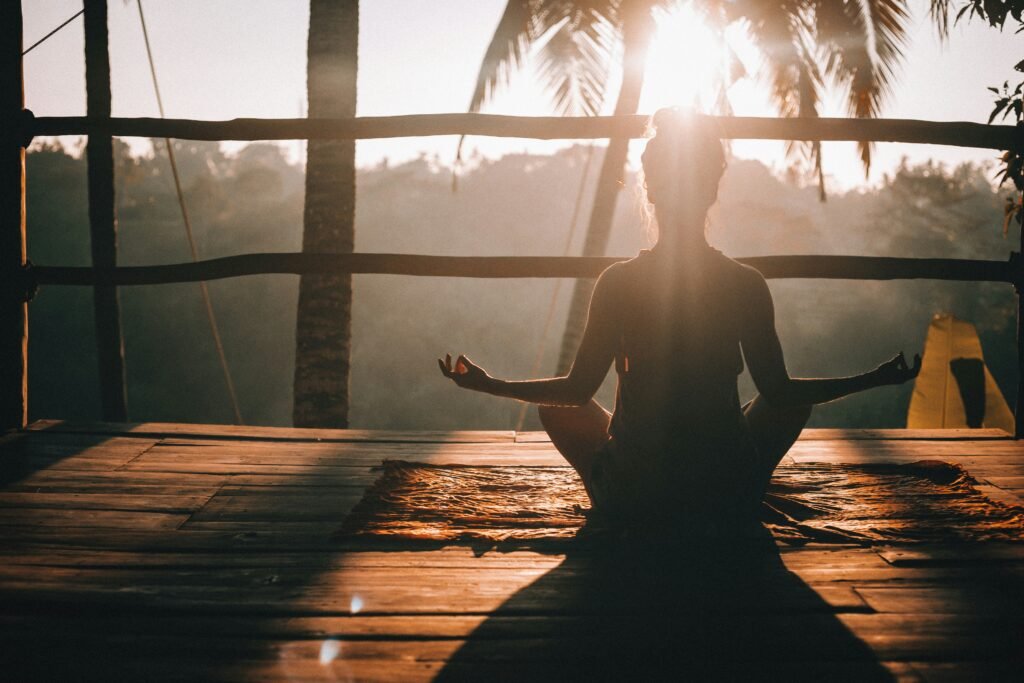 Pessoa praticando meditação em casa, ao nescer do sol, em ambiente tranquilo