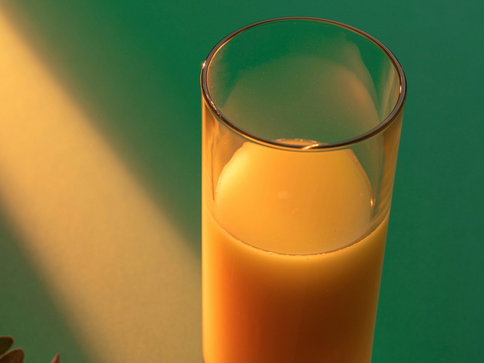 Copo de vidro de suco de abóbora em um fundo verde